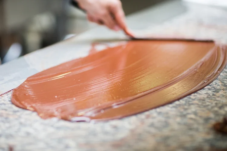 Du chocolat est étalé sur le marbre avec une spatule.