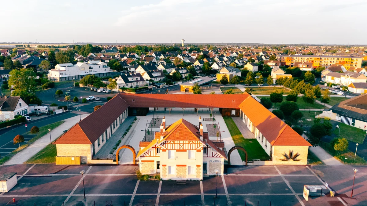 Vue aérienne de bâtiments aux toits rouges autour d’une cour, avec un pavillon à colombages au premier plan à Giberville.