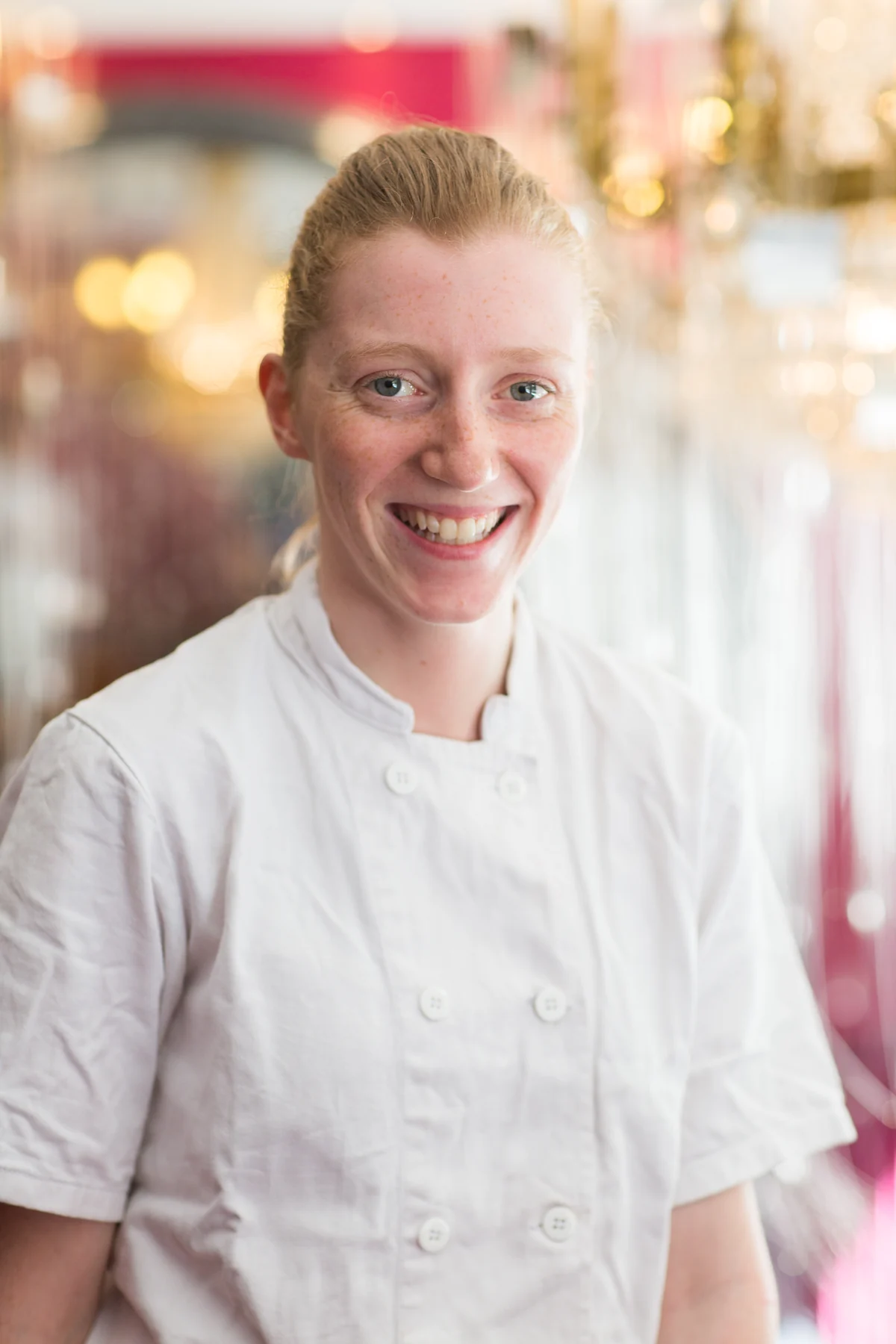 Portrait souriant d’une femme en veste blanche chez Stiffler.